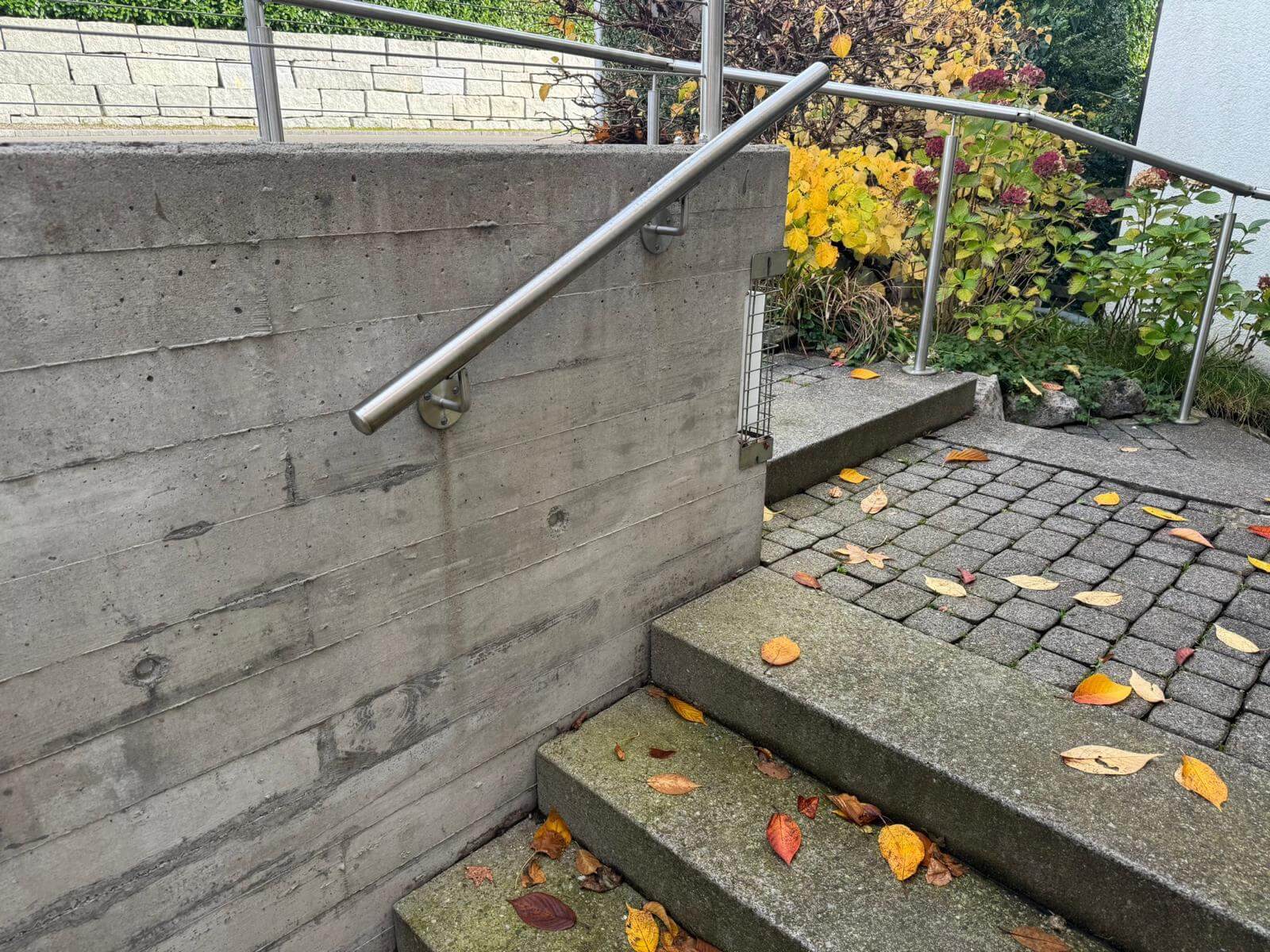 Edelstahl Wandhandlauf an einer Betonwand an der Treppe montiert - Handlaufpro