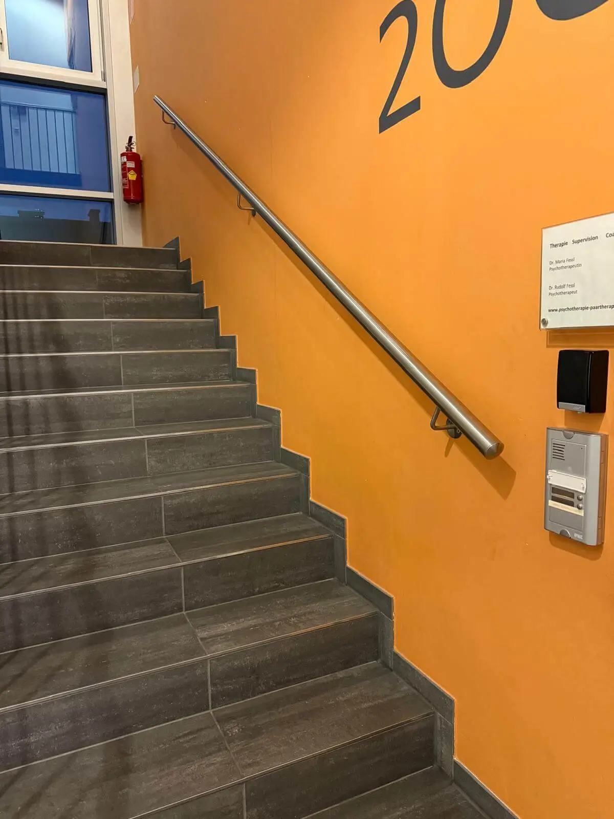 Treppe mit Edelstahl Wandhandlauf mit der orange Farbe - handlaufPRO